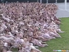 A large group of naked ladies were posing in a public place during the afternoon