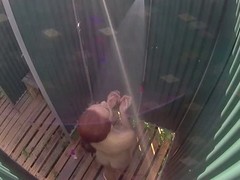 Adorable girl is taking a bath in a public shower on the beach, in front of the camera