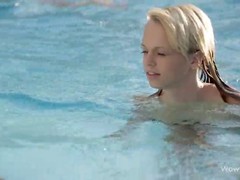 Two cute girls are touching each other in the swimming pool and enjoying it a lot