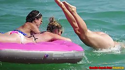 Topless ladies are enjoying on the beach while guys are staring at their bouncy tits