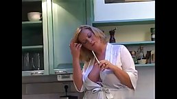 Voluptuous blonde woman is playing with her big tits in the kitchen, and loving it