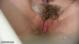 Insatiable teen babe with a hairy pussy likes cuddling her tits, while having a nice bath time
