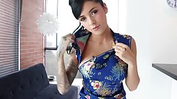 Tattooed Asian brunette in a satin dress is spreading her legs wide and masturbating like crazy