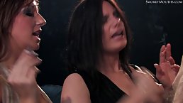 Kinky women are smoking and taking turns sucking a stiff dick, while kneeling on the floor