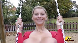 Blonde woman with big tits is using the swing in the public park and being very naughty