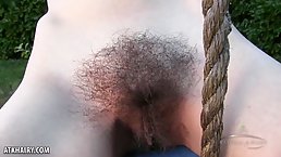 Aislynn is completely naked while using a swing and spreading up to display her hairy pussy