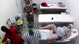 Mature woman is holding her legs spread wide open while girls are having an epilation course