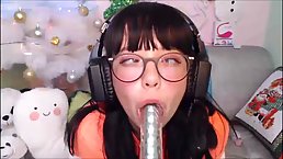 Cute teen brunette with braces is sucking a huge dildo, in front of the camera