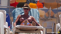 Topless chick doesn't give a fuck that everyone is staring at her tits, on the beach