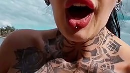 Tattooed brunette is eagerly sucking a big, fake dick in the middle of the day