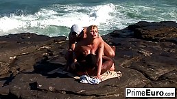 Hot, German blonde with big boobs is having an interracial threesome on the beach, during the day