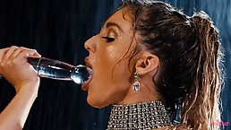 Hot woman with big tits is masturbating in front of the camera with a big, glass dildo
